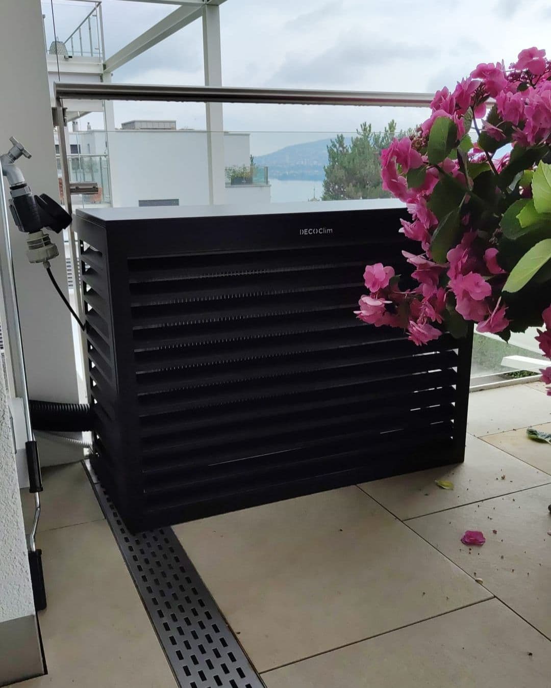 Dunkle Design-Abdeckung über einem Aussengerät auf einem Balkon mit Seeblick