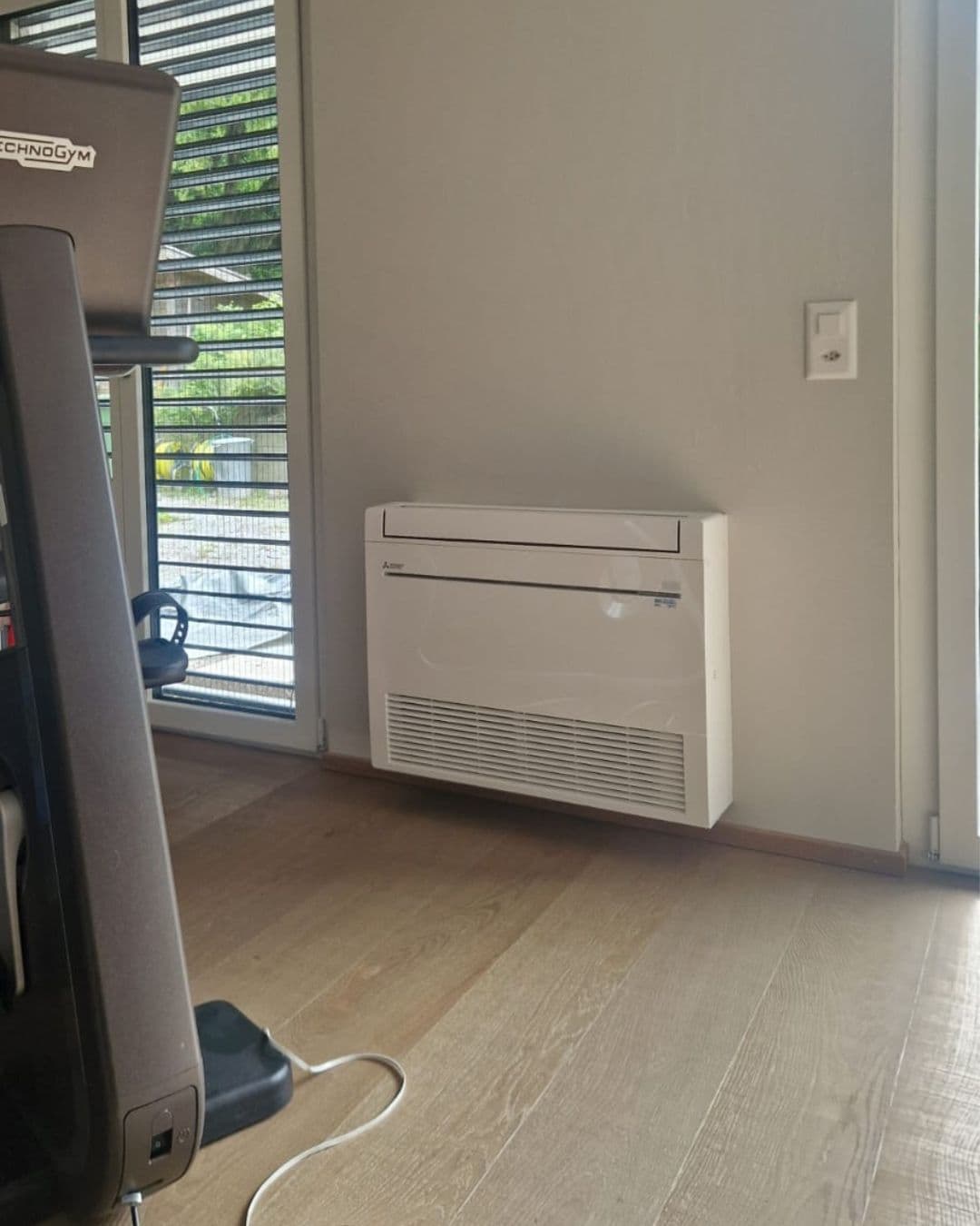 Truhengerät von Mitsubishi Electric im Fitnessraum, neben einem Laufband