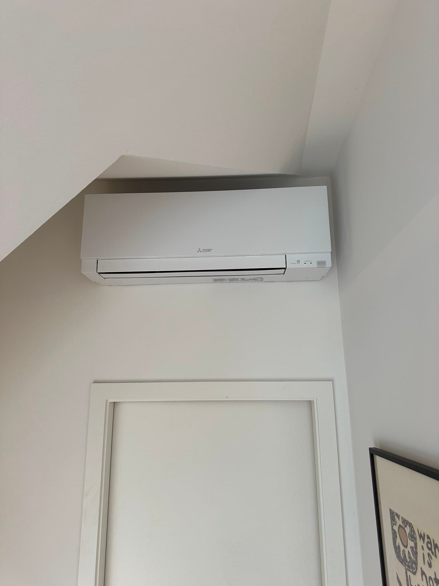 Weisses Wandklimagerät sauber unter der Dachschräge montiert, Wohnraum im Kanton Zürich