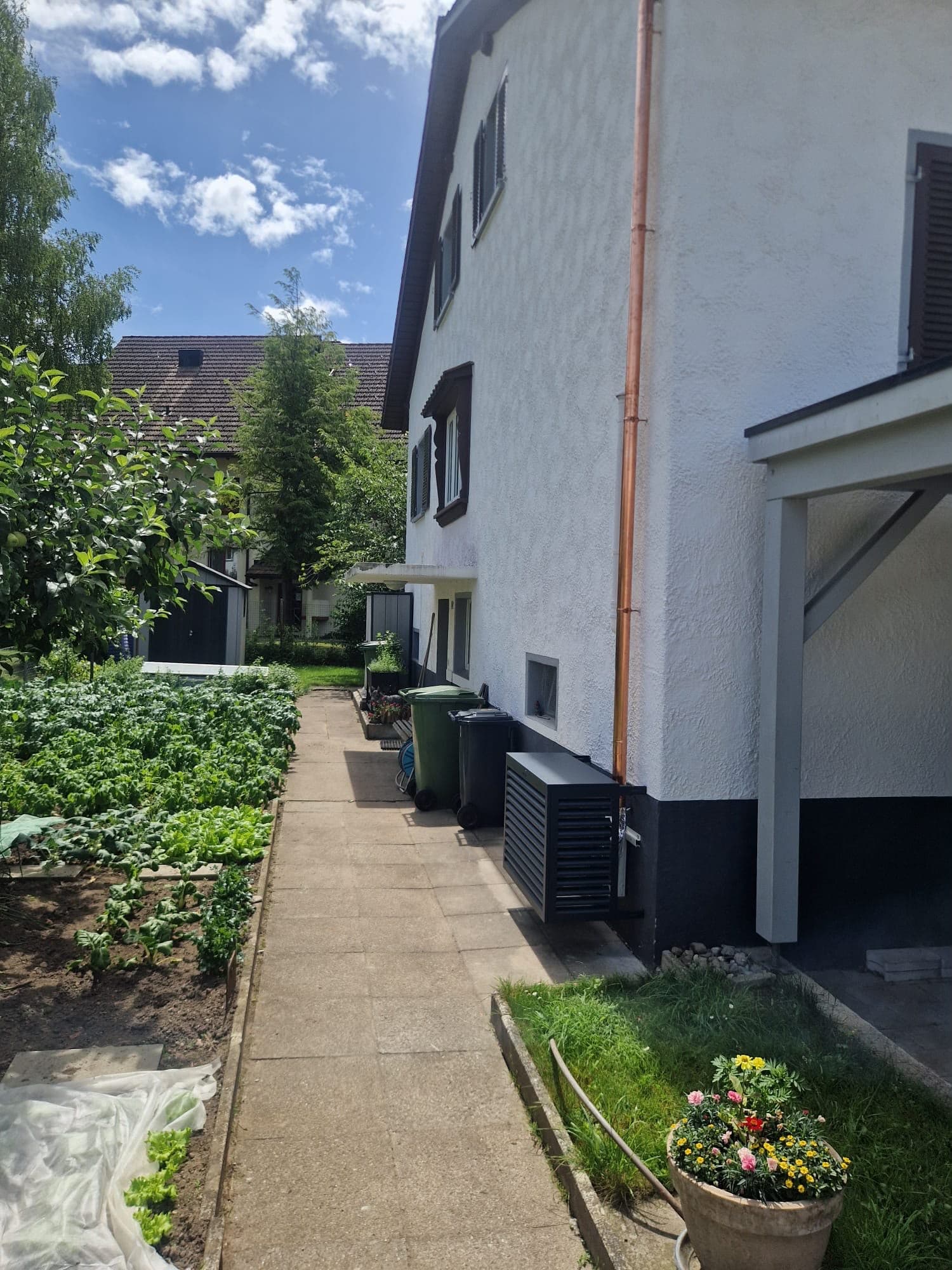 Aussengerät einer Wärmepumpe entlang der Hauswand mit Garten, Kanton Zürich